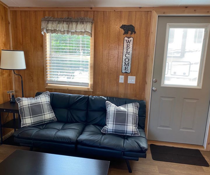 Yogi Bear cabin interior with lamp, futon, coffee table, window, and door