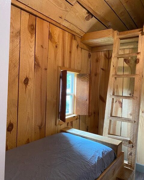 6 person cabin with bed, window, and ladder leading to loft