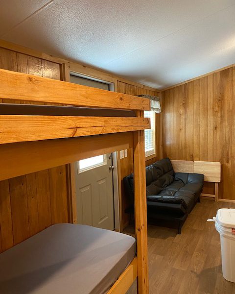 Ranger Smith cabin interior with bunk beds, futon, TV tray tables, and trash bin