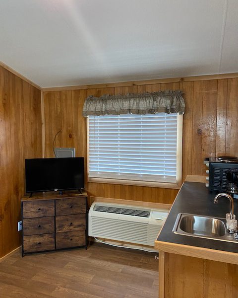 Ranger Smith cabin interior with TV, drawers, heater, countertop, toaster oven, and sink