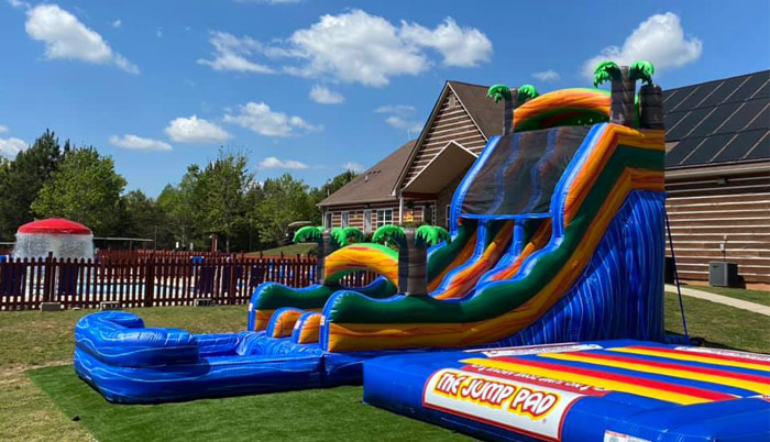 Large inflatable slide and jump pad on grassy field