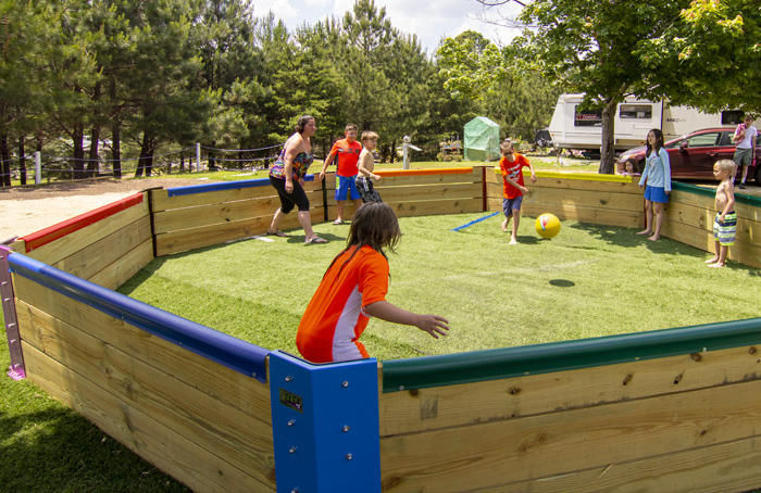 Children playing gaga ball in an enclosed octagonal grassy area