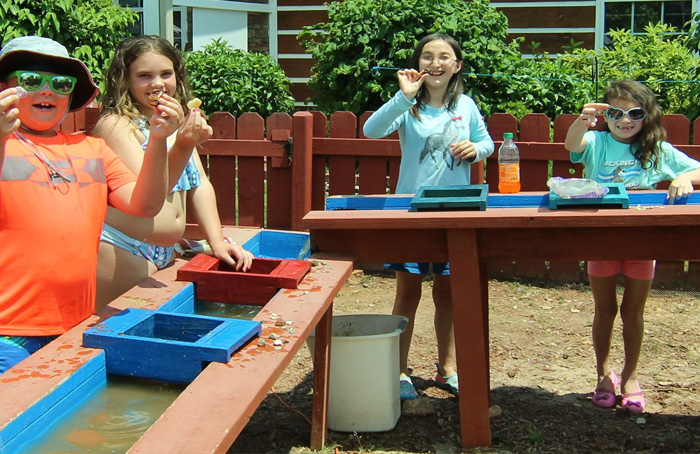 4 smiling children participating in a gem sifting activity